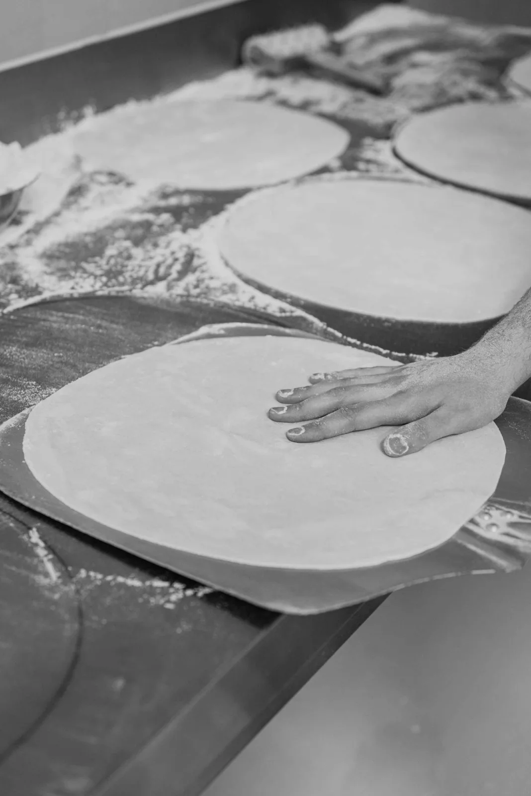 Masa de pizza estirada a mano en el obrador de El Deseo Artesano